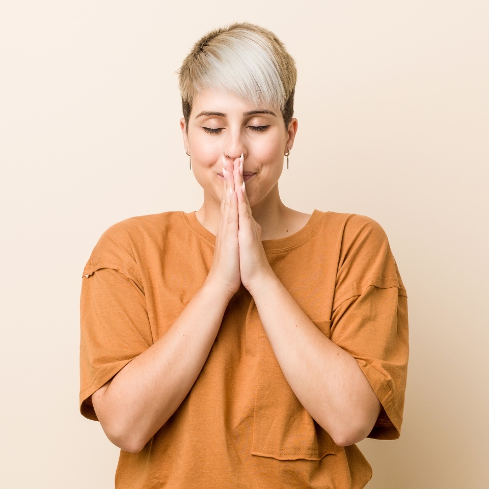 Young plus size woman with short hair holding hands in pray near mouth, feels confident.