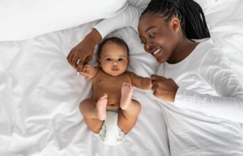 African American mom lying in bed with her cute infant