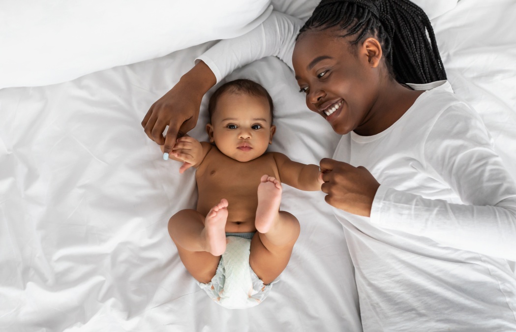 African American mom lying in bed with her cute infant