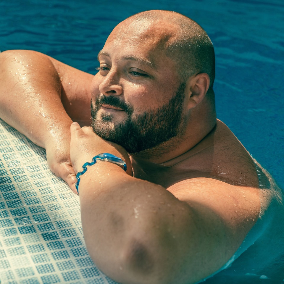 Portrait of plus size big happy smiling man relaxing in swimming pool