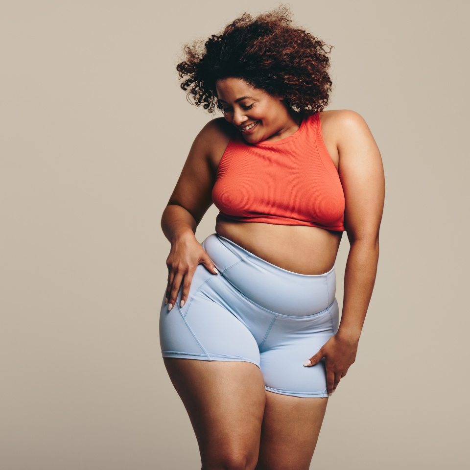 Woman in sportswear showing her physical fitness and flexibility through dance. With a confident expression, she celebrates her fitness journey, proving that body positivity is truly empowering.