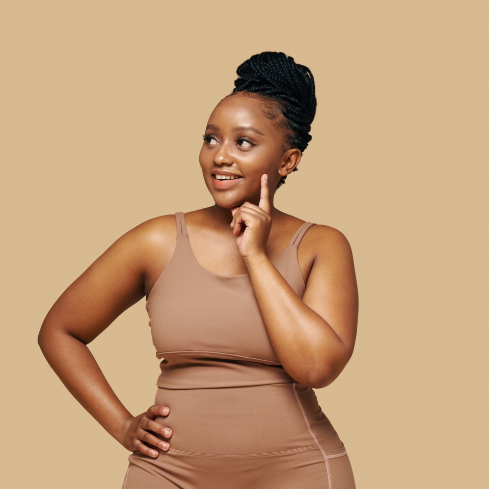 Studio portrait of smiling pensive Black woman in shapewear looking away