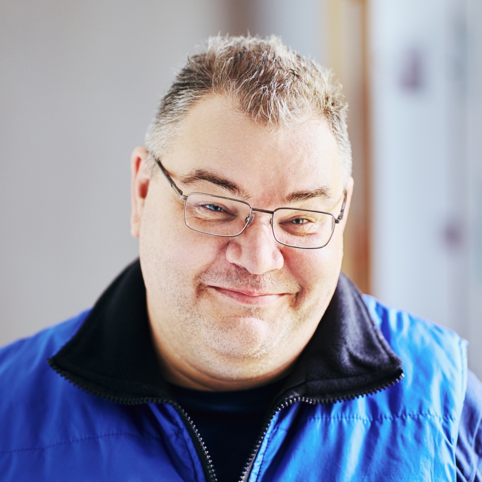 Good natured face of chubby Caucasian man in her 40s wearing glasses.