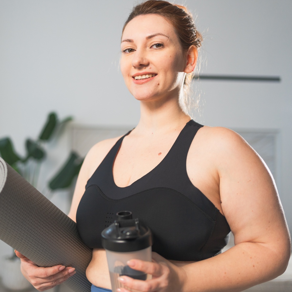 Yoga fitness sport workout training. Woman hold yoga mat bottle water ready for practicing yoga at home. Plus size female doing sports indoor. Girl in sportswear have training workout for weight loss
