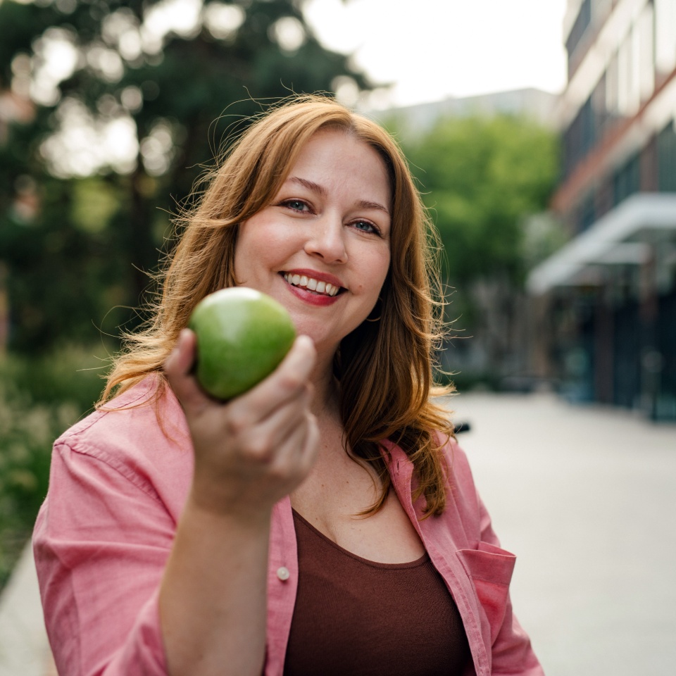Plus size woman holding green apple.