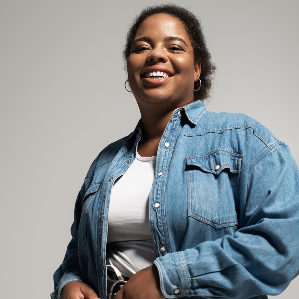 A confident plus size African American woman showcases her trendy autumn outfit in a studio.