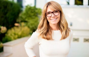 Confident, slim, smiling mature woman standing in front yard of home