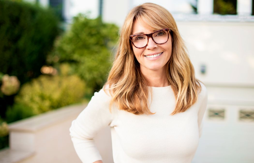 Confident, slim, smiling mature woman standing in front yard of home