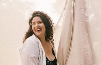 A radiant plus size woman enjoying a moment of pure joy in a lush, sunny field filled with nature.